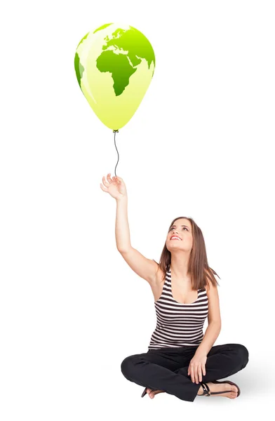 Happy lady holding a green globe balloon — Stock Photo, Image