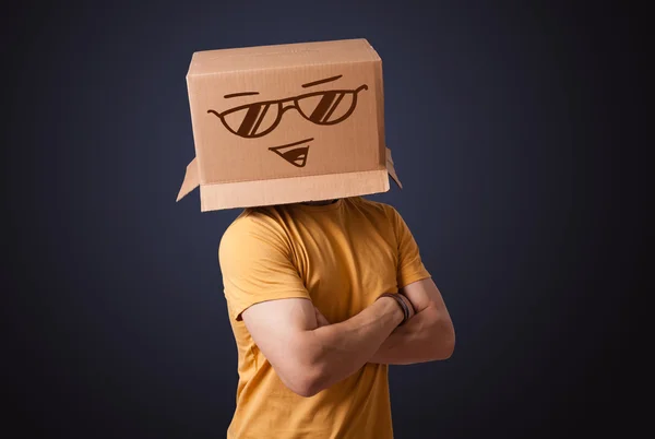 Junger Mann gestikuliert mit einem Pappkarton auf dem Kopf mit Smiley — Stockfoto