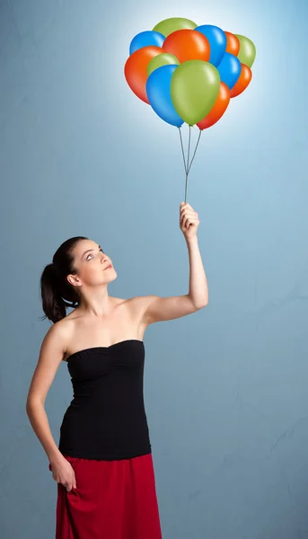 Νεαρή γυναίκα που κρατά πολύχρωμα μπαλόνια — Φωτογραφία Αρχείου