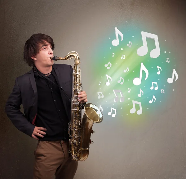 Jeune musicien jouant sur saxophone tandis que les notes de musique explosent — Photo