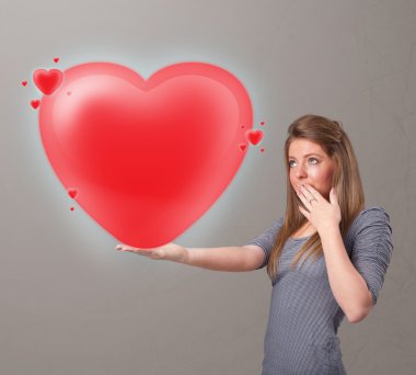 Genç bir bayan 3 boyutlu kırmızı bir kalp taşıyor.