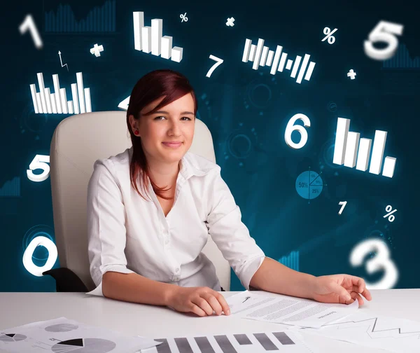 Молодая деловая женщина сидит за столом с диаграммами и статистикой — стоковое фото