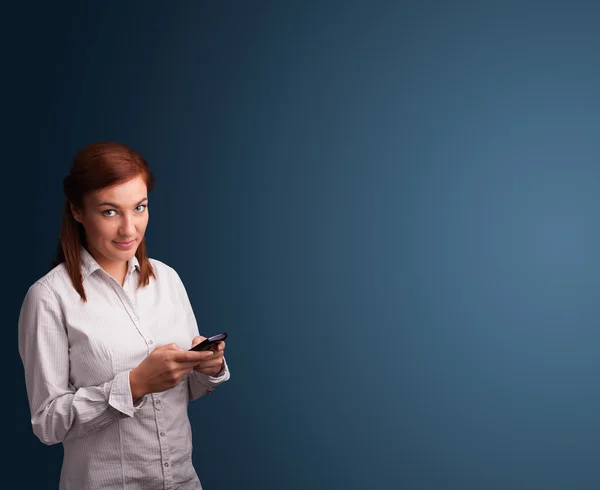 Junge Frau steht und tippt auf ihrem Handy mit Kopierplatz — Stockfoto