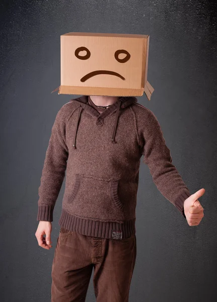 Young man with a brown cardboard box on his head with sad face — Stock Photo, Image