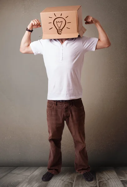 Joven haciendo gestos con una caja de cartón en la cabeza con luz — Foto de Stock