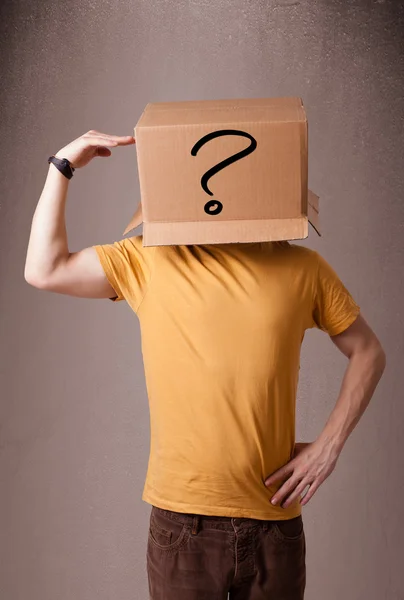 Young man gesturing with a cardboard box on his head with questi — Stock Photo, Image