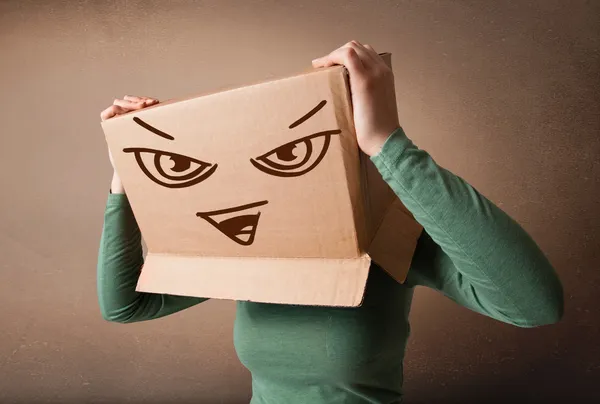 Молода жінка жестикулює картонною коробкою на голові зі злом — стокове фото