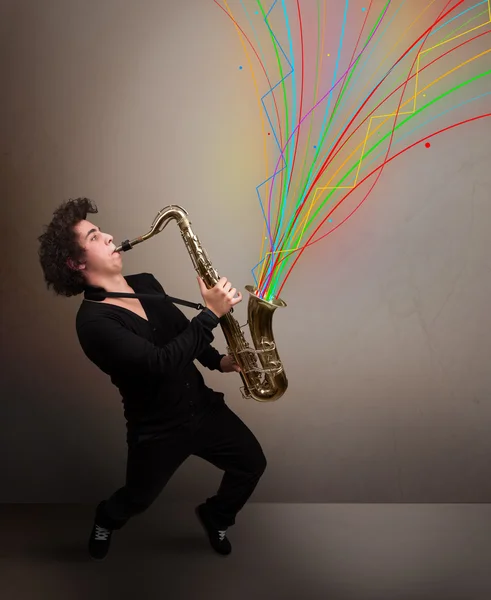 Atractivo músico tocando en el saxofón mientras colorido abstracto — Foto de Stock