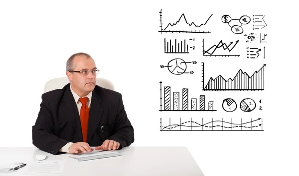 Businessman sitting at desk with statistics and graphs — Stok fotoğraf