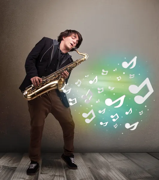 Joven músico tocando el saxofón mientras las notas musicales explotan —  Fotos de Stock