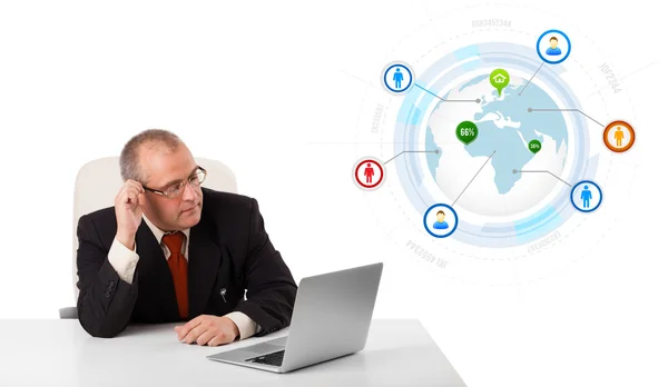 Businessman sitting at desk and looking laptop with globe and so — Stock Photo, Image