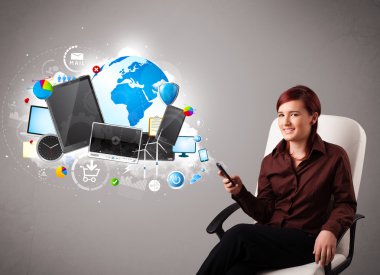 Genç bir kadın oturuyor ve telefonuna bakıyor.