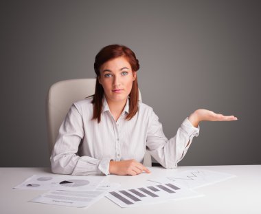 İş kadını masada oturuyor ve evrak işleriyle uğraşıyor.