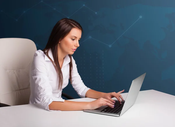 Jeune femme assise au bureau et tapant sur un ordinateur portable — Photo