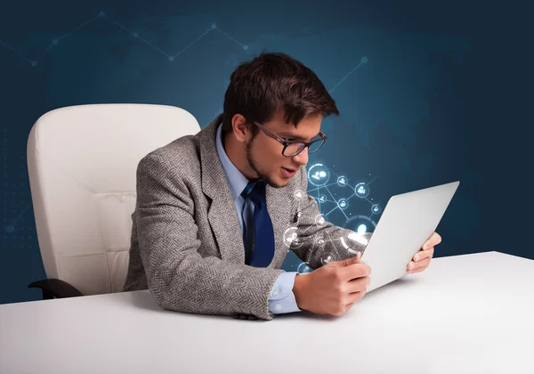 Jovem sentado na mesa e digitando no laptop com rede social — Fotografia de Stock