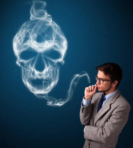 Young man smoking dangerous cigarette with toxic skull smoke — Stock Photo, Image