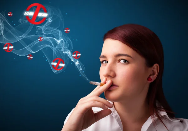 Young woman smoking dangerous cigarette with no smoking signs — Stock Photo, Image