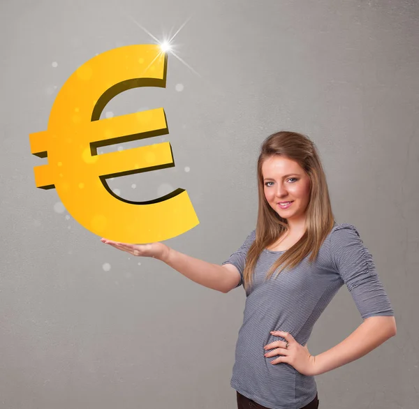 Hermosa chica sosteniendo un gran signo de oro en 3D euro —  Fotos de Stock