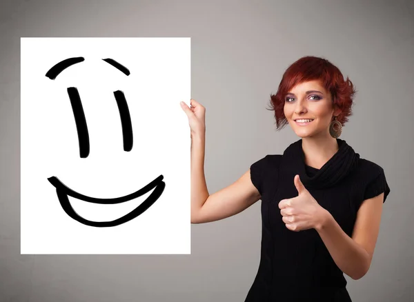 Jovem mulher segurando sorridente desenho rosto — Fotografia de Stock