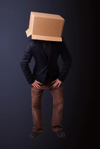 Kafasında karton bir kutuyla el kol hareketi yapan genç bir adam. — Stok fotoğraf