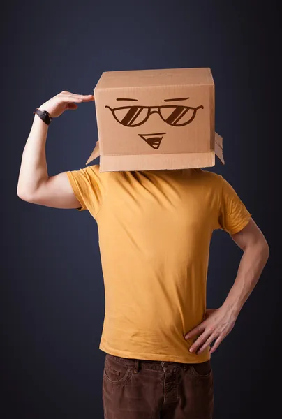Fiatal férfi intett egy karton doboz, smiley-val a fején — Stock Fotó