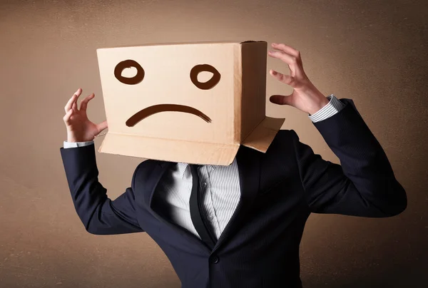 Бізнесмен жестикулює з картонною коробкою на голові з сумним фа — стокове фото