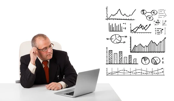 Üzletember ülő-on iskolapad-grafikonok és laptop — Stock Fotó