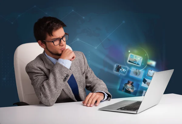 Young man sitting at desk and watching his photo gallery on lapt — Stock Photo, Image