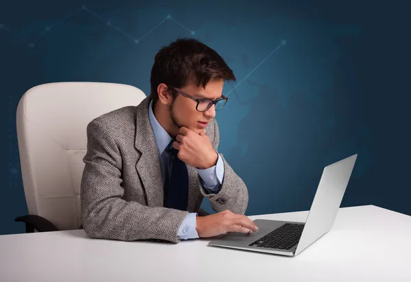 Jongeman zit achter het bureau en typt op laptop — Stockfoto