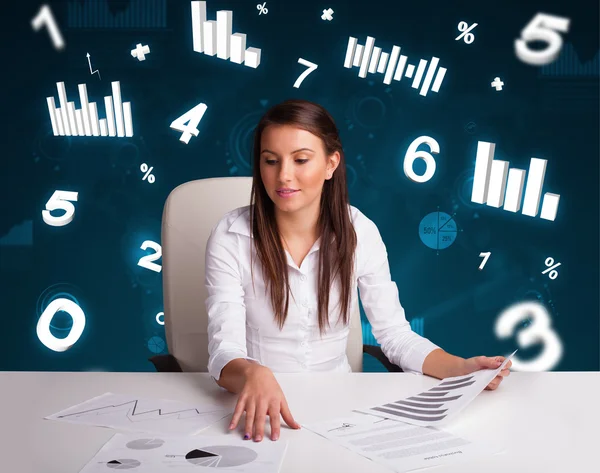 Jovem empresária sentada à mesa com diagramas e estatísticas — Fotografia de Stock