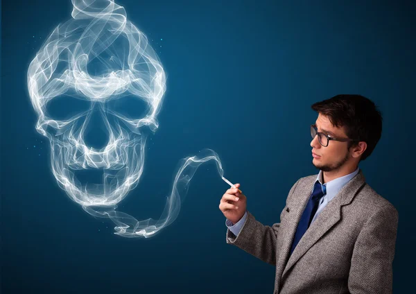 Young man smoking dangerous cigarette with toxic skull smoke — Stock Photo, Image