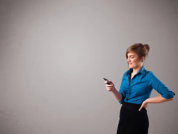 Young lady standing and holding a phone with copy space — Stock Photo, Image