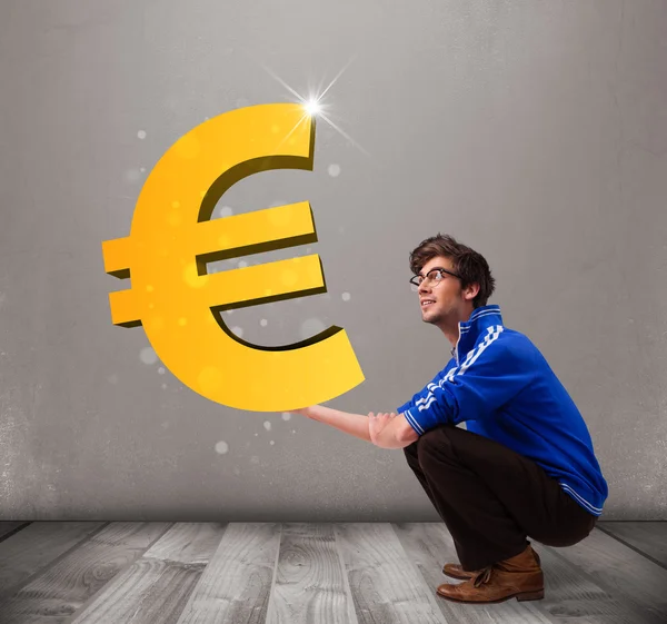 Good-looking boy holding a big 3d gold euro sign — Stock Photo, Image