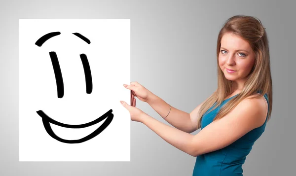 Jovem mulher segurando sorridente desenho rosto — Fotografia de Stock