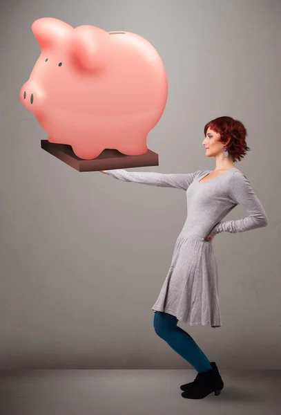 Jovem segurando uma enorme poupança porquinho banco — Fotografia de Stock