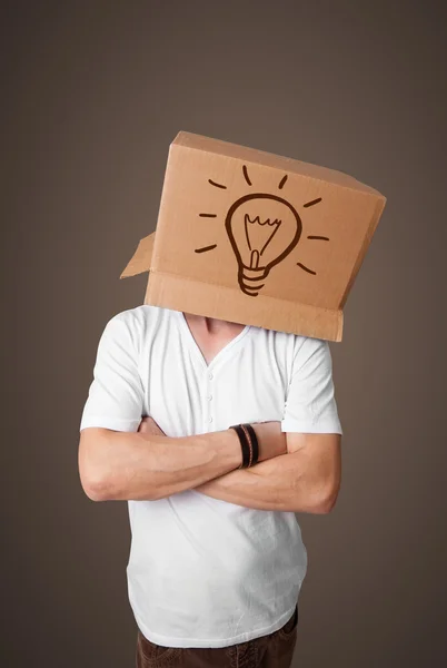 Young man gesturing with a cardboard box on his head with light — Stock Photo, Image