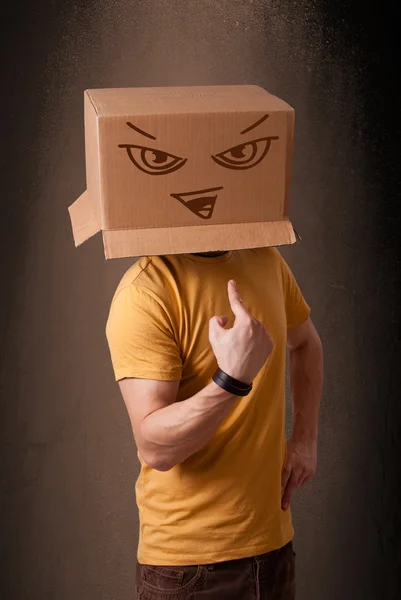 Young man gesturing with a cardboard box on his head with evil f — Stock Photo, Image