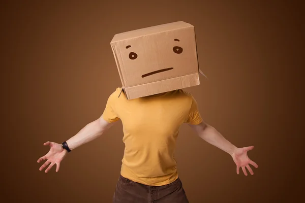 Young man gesturing with a cardboard box on his head with straig — Stock Photo, Image