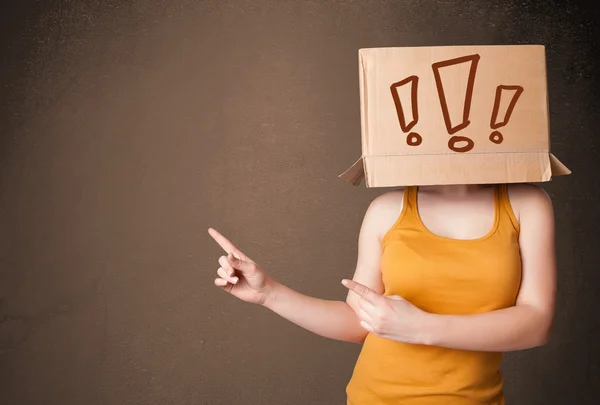 Señorita haciendo gestos con una caja de cartón en la cabeza con excla — Foto de Stock