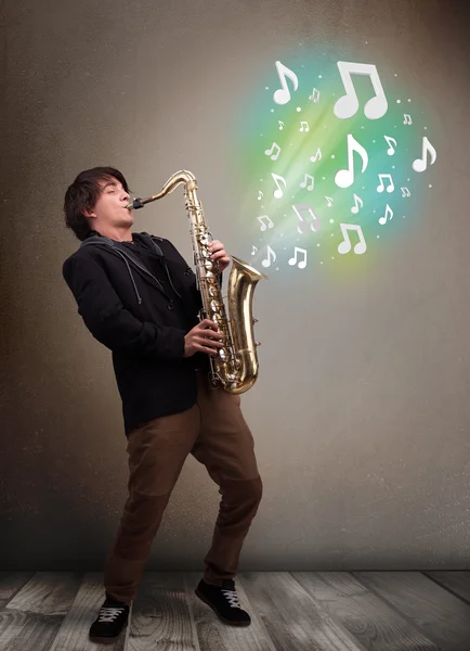 Young musician playing on saxophone while musical notes explodin — Stock Photo, Image