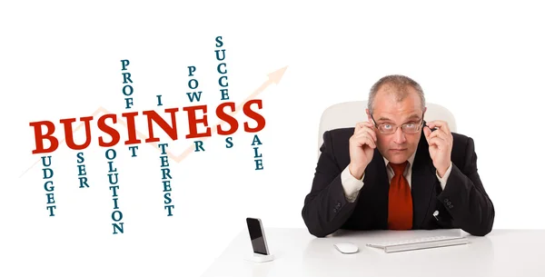 Businesman sitting at desk with business word cloud — Stock Photo, Image