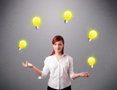 Genç bayan ayakta ve ampullerle hokkabazlık yapıyor.