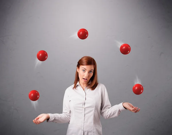 Молода дівчина стоїть і жонглює з червоними кульками — стокове фото