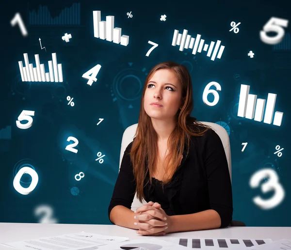 Junge Geschäftsfrau sitzt am Schreibtisch mit Diagrammen und Statistiken — Stockfoto