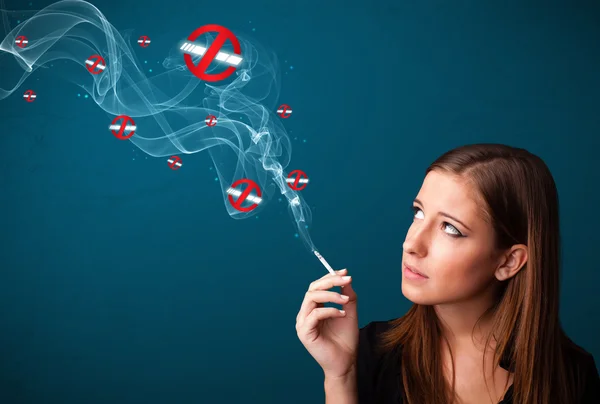 Young woman smoking dangerous cigarette with no smoking signs — Stock Photo, Image