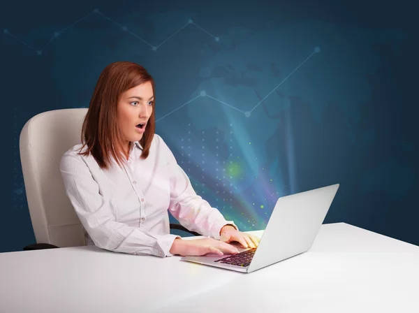 Hermosa mujer sentada en el escritorio y escribiendo en el ordenador portátil con abstra —  Fotos de Stock