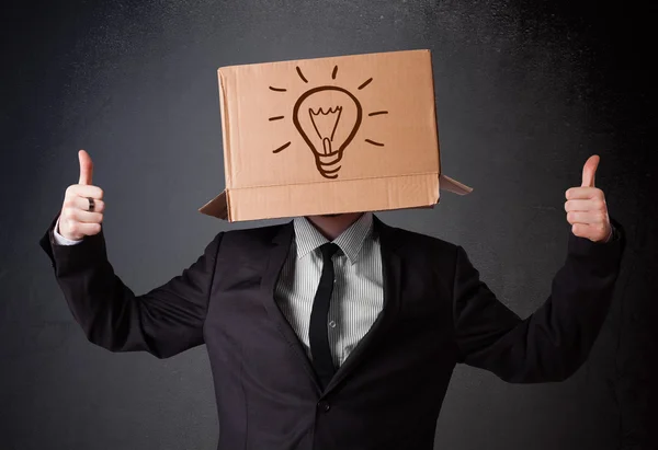 Businessman gesturing with a cardboard box on his head with ligh — Stock Photo, Image