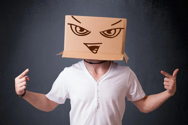 Young man gesturing with a cardboard box on his head with evil f — Stock Photo, Image