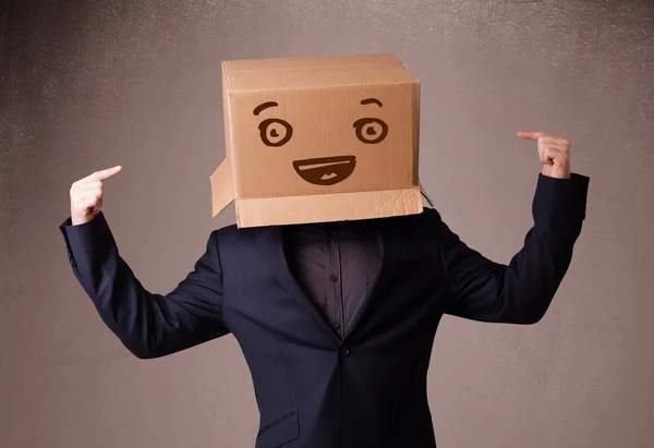 Joven haciendo un gesto con una caja de cartón en la cabeza con sonriente —  Fotos de Stock