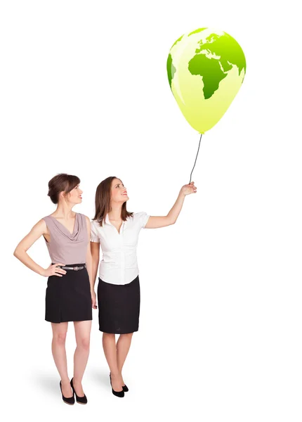 Happy ladies holding a green globe balloon — Stock Photo, Image